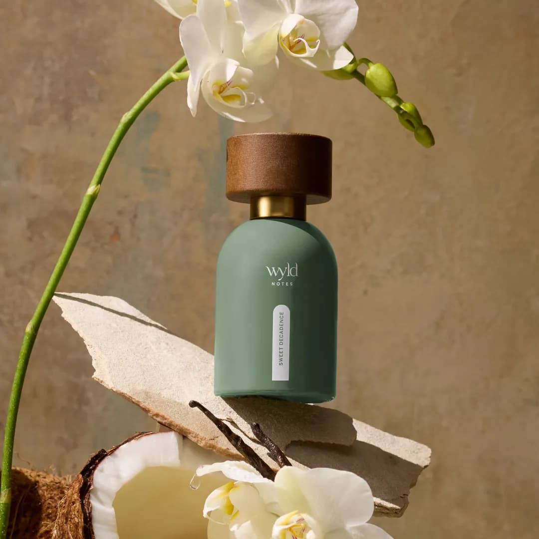 Wyld Notes Sweet Decadence next to an orchid and a cracked coconut