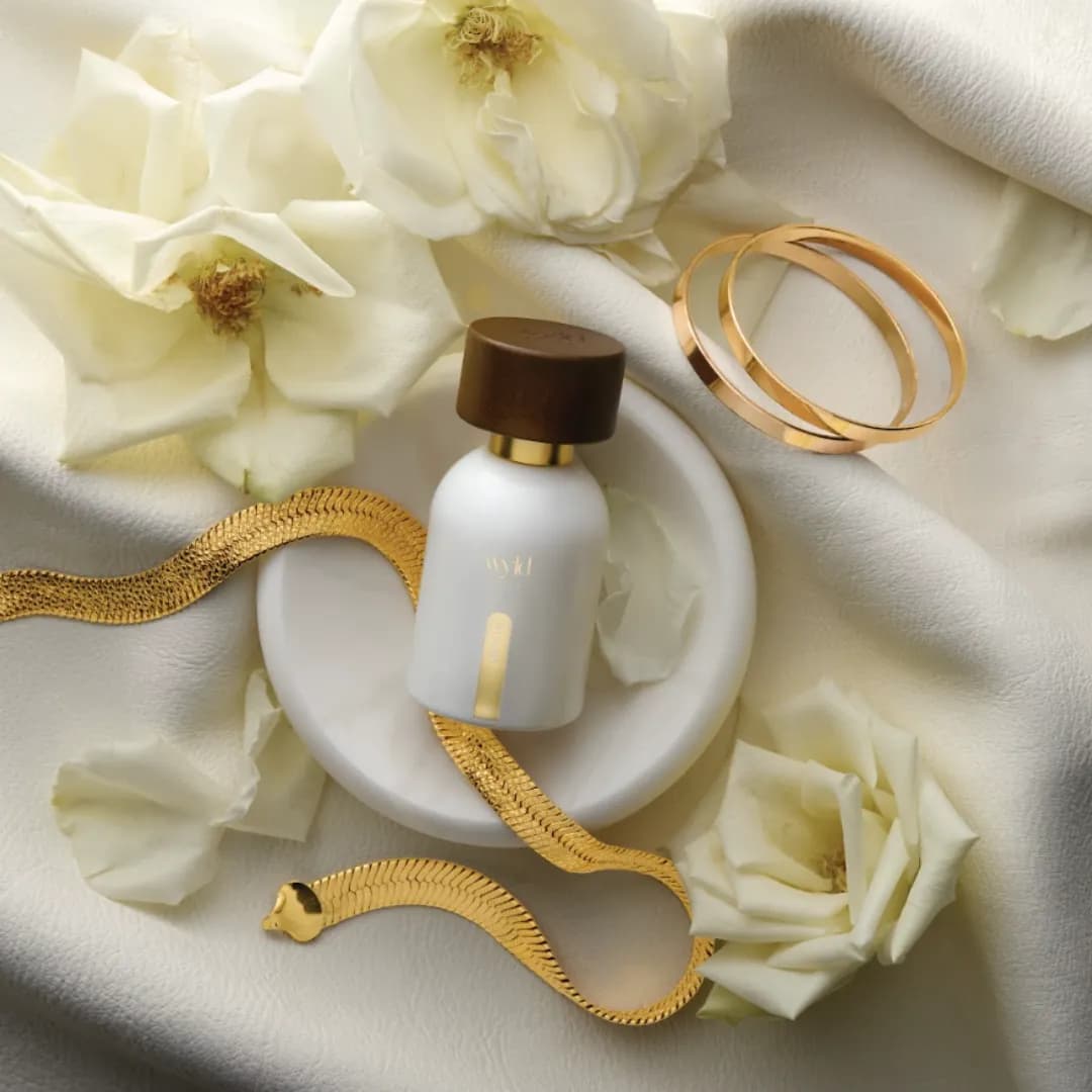 Wyld Notes White Lie lying among white roses and a gold bracelet